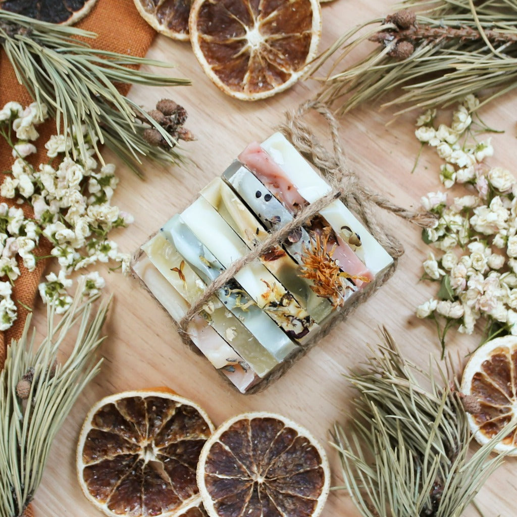 Ensemble de huit échantillons de savons artisanaux naturels, colorés naturellement avec plantes et argiles, décoré d'orange et de pin, attachés ensemble avec cordelette