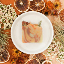 Load the image into the gallery, Savon artisanal naturel Clairière ensoleillée, coloré mauve, rose et orange, décoré de pin, fleurs et orange
